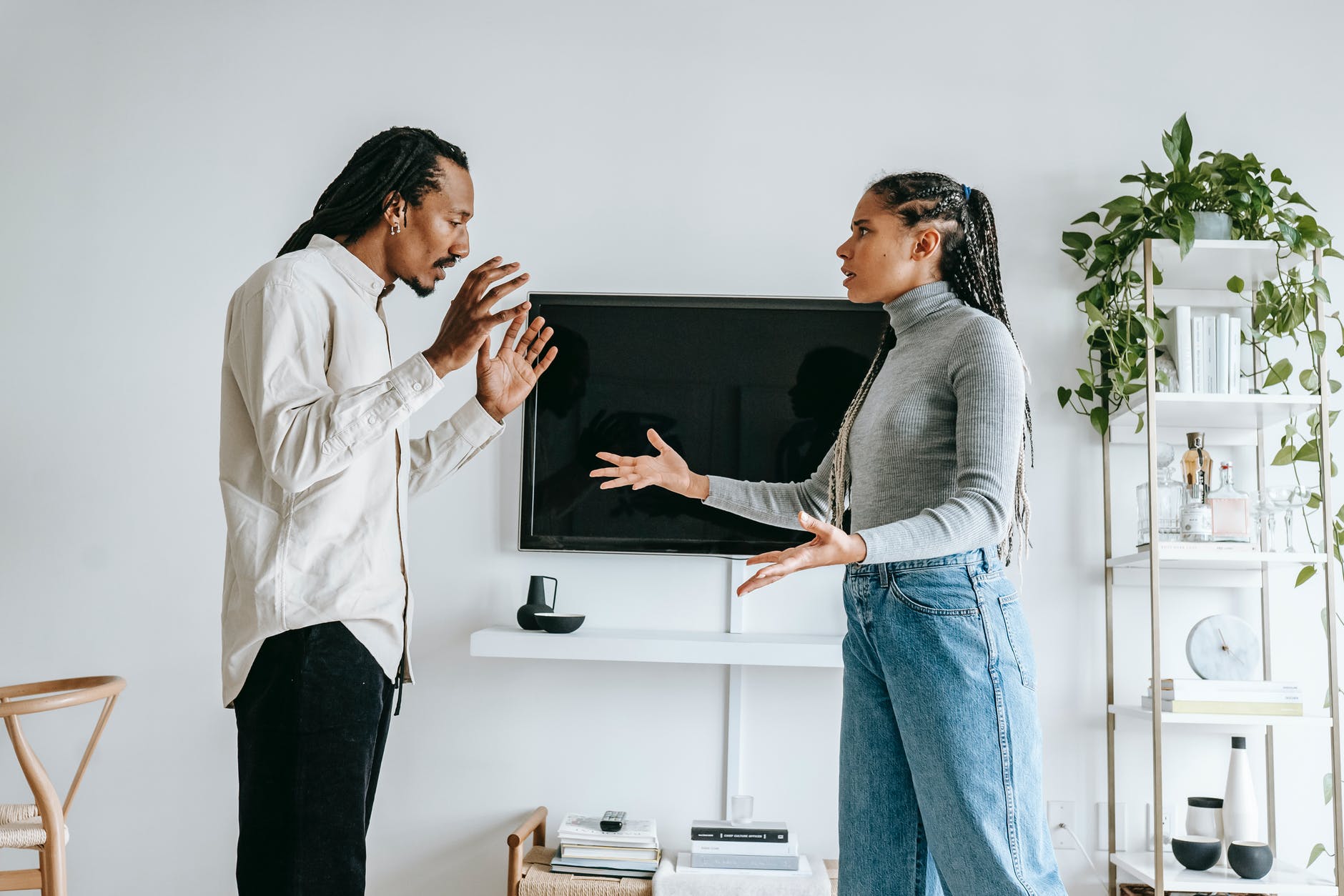 annoyed young ethnic couple quarreling in cozy apartment